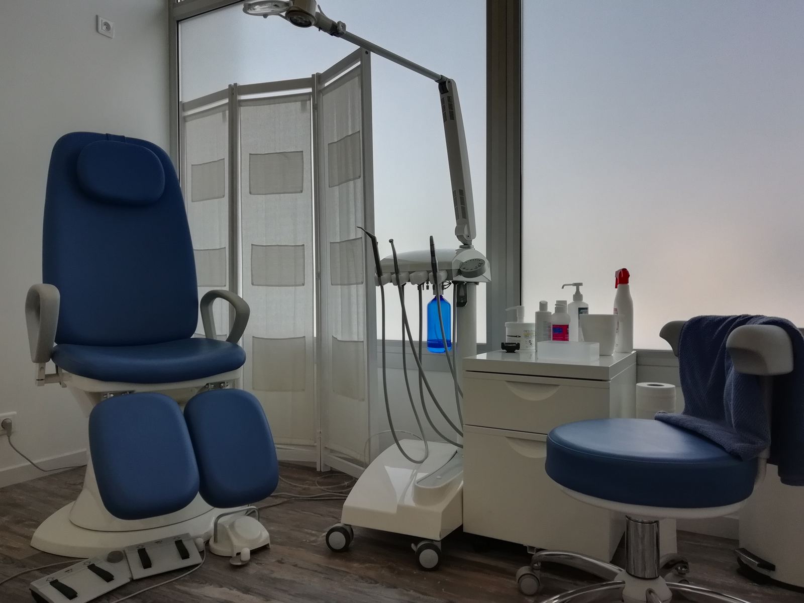 Fauteuil de soins bleu et unité de pédicurie dans la salle de soins lumineuse du cabinet